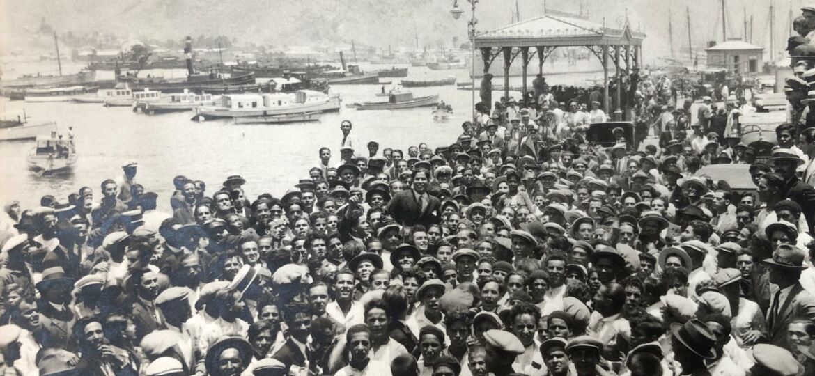 Centenares de aficionados, congregados el 10 de julio de 1928 en la vieja marquesina del puerto de Santa Cruz de Tenerife para recibir a Ángel Arocha, que aparece izado a hombros en el centro de la foto (FONDO CDT/LEGADO AROCHA)